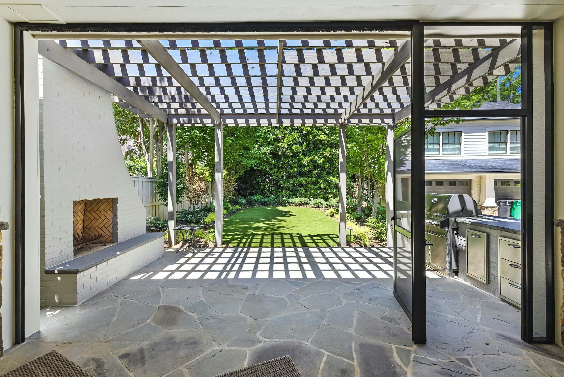 Modern outdoor living space with pergola, fireplace, and outdoor kitchen