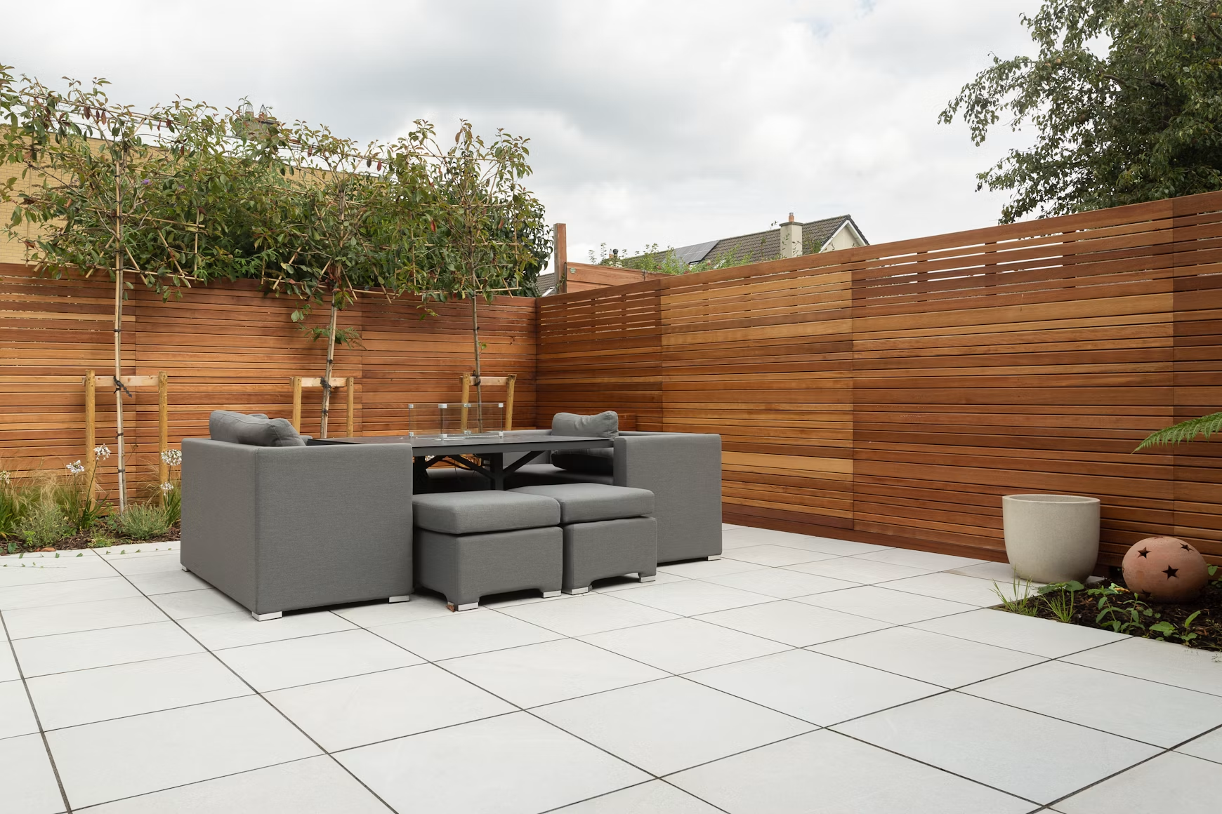 Modern paver patio with gray sectional seating and cedar privacy fence